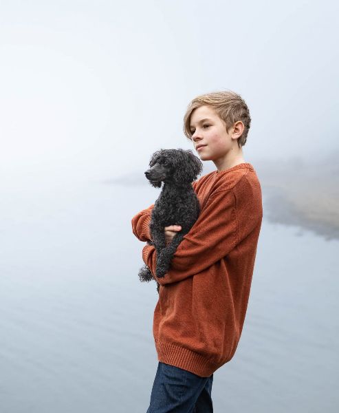 Fotografering vid havet under vårvintern Pojke med hund i famnen